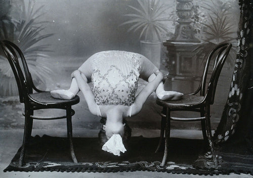 A Bulgarian female acrobat performing contortions with a handkerchief in her mouth. c, 1900