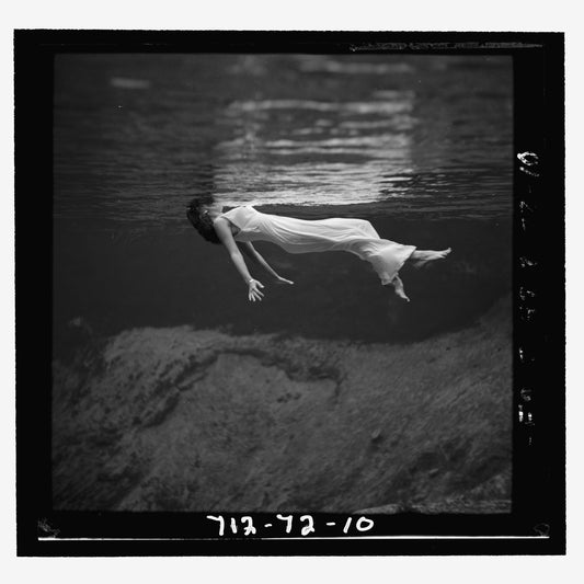 A woman, wearing a long gown, floating in water by Toni Frissell - 1947