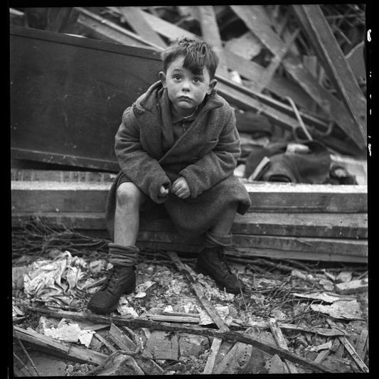Boy seated in wreckage of building after a bombing raid of London during World War II January 1945