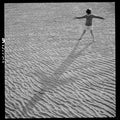 A boy standing on a beach looking at his shadow by Toni Frissell - 1944