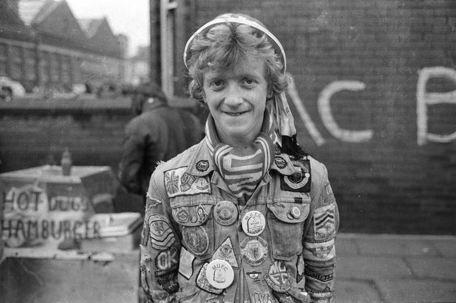 Manchester United Fan with Badges and Hat by Iain SP Reid - c. 1976